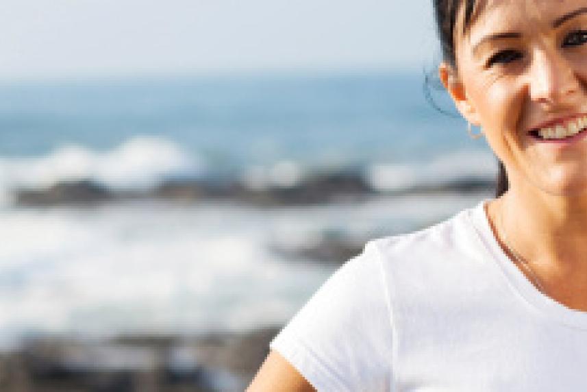 Photo: Woman smiling at camera with ocean in background