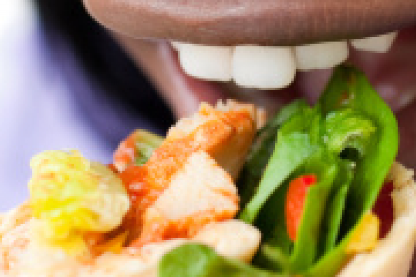 Photo: Woman taking a bit of a crispy chicken wrap