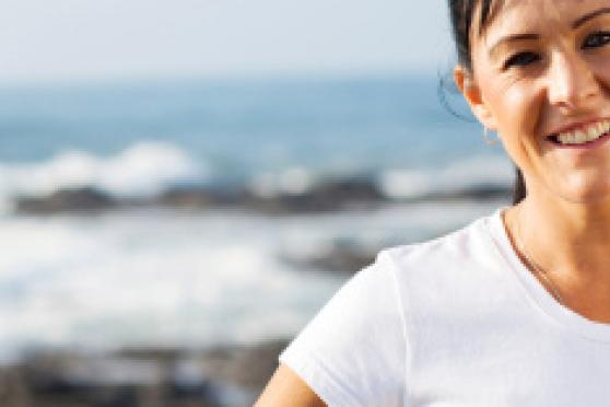 Photo: Woman smiling at camera with ocean in background